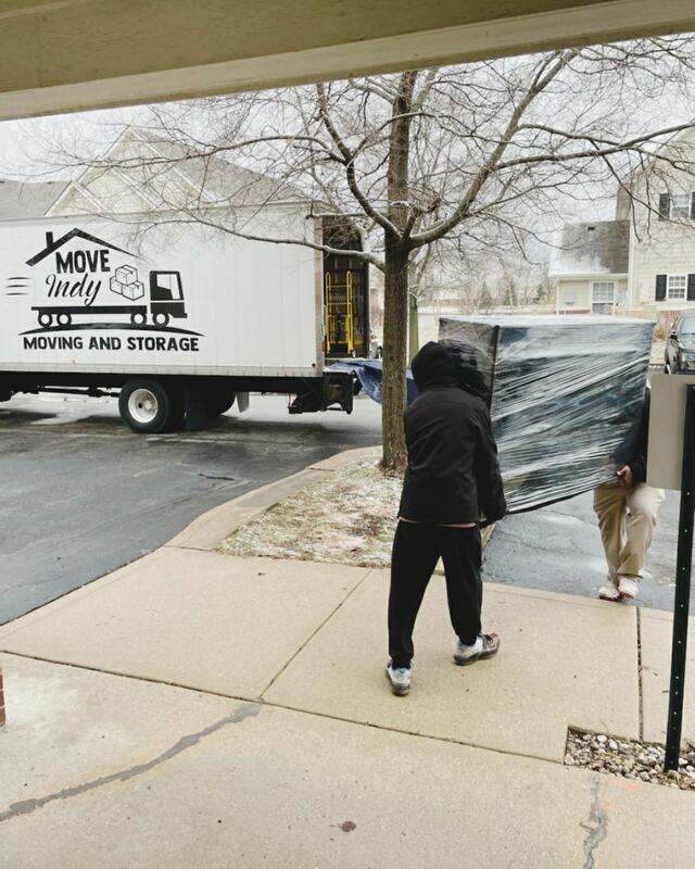Indianapolis movers from Move Indy carry heavy furniture to their moving truck.