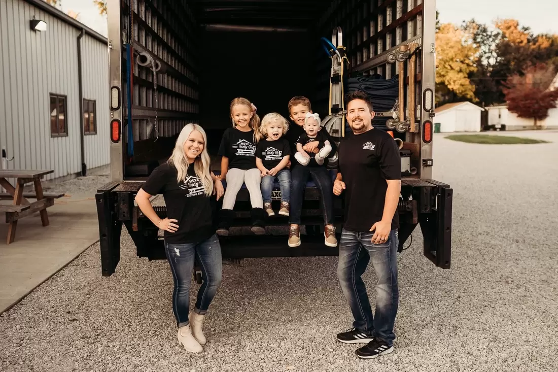 Local Indianapolis moving company owners, Caleb and Meghan, pose with their children on the back of their moving truck.