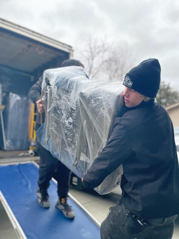 Move Indy movers in Indianapolis work together to carry heave furniture up the truck ramp.