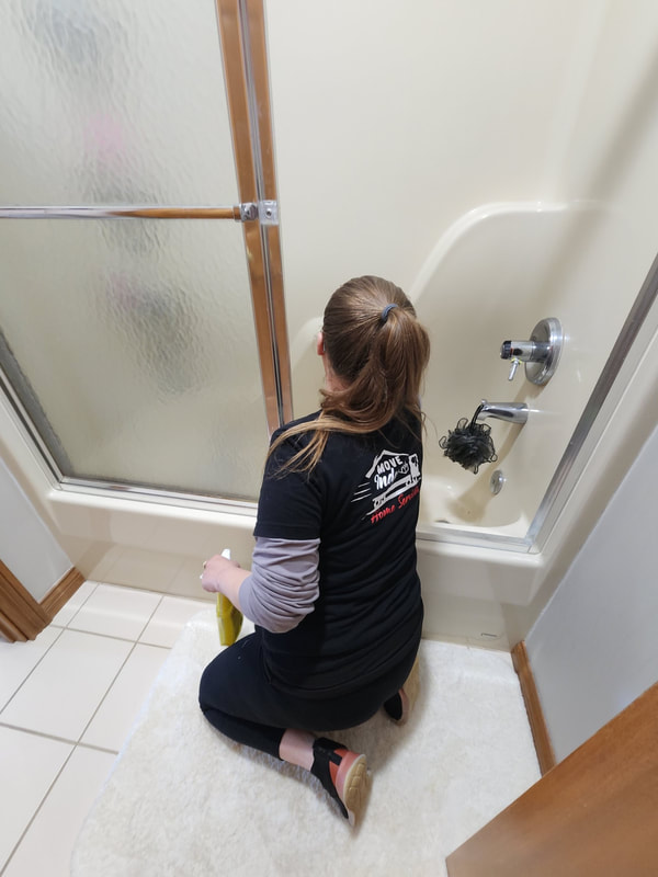 A professional home cleaner from Move Indy cleans the bathtub.